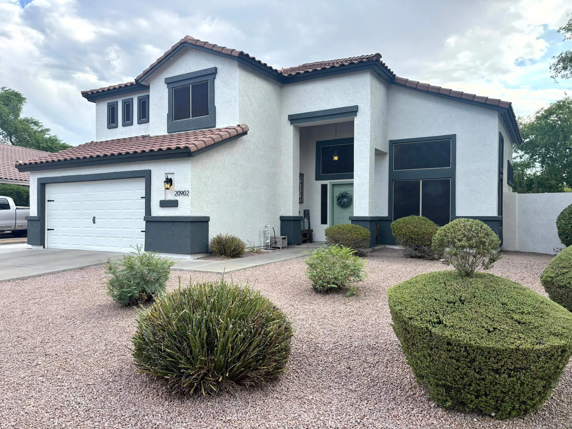 Modern two-story residential home featuring a white stucco exterior with dark charcoal trim and a white garage door, professionally painted by Butchers Custom Painting.