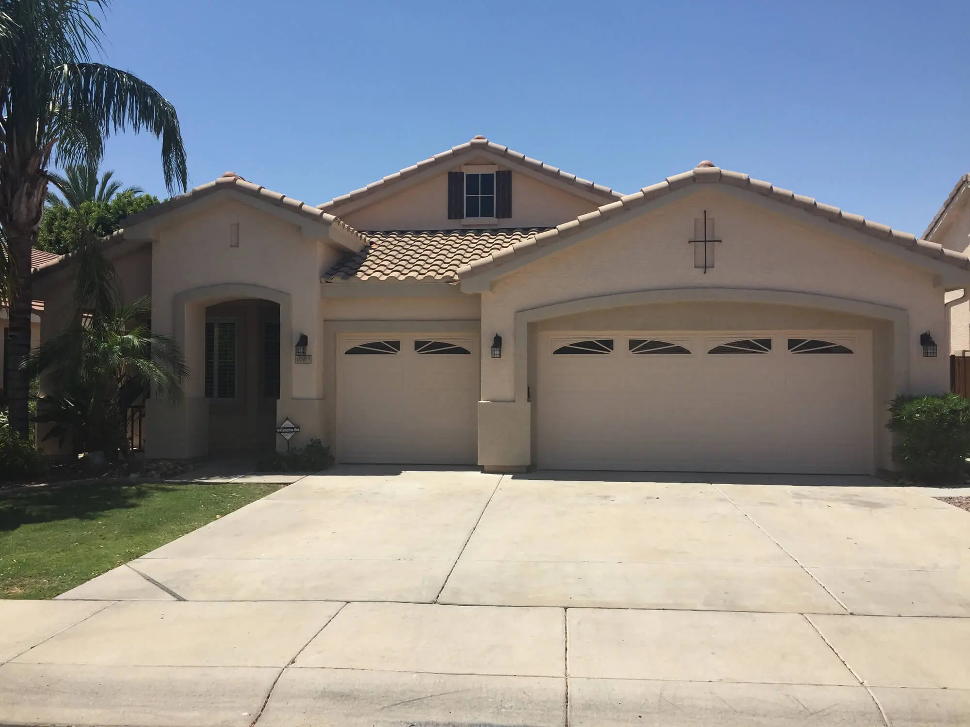Modern single-story stucco home featuring a tan exterior and matching garage doors, professionally finished by Butchers Custom Painting.