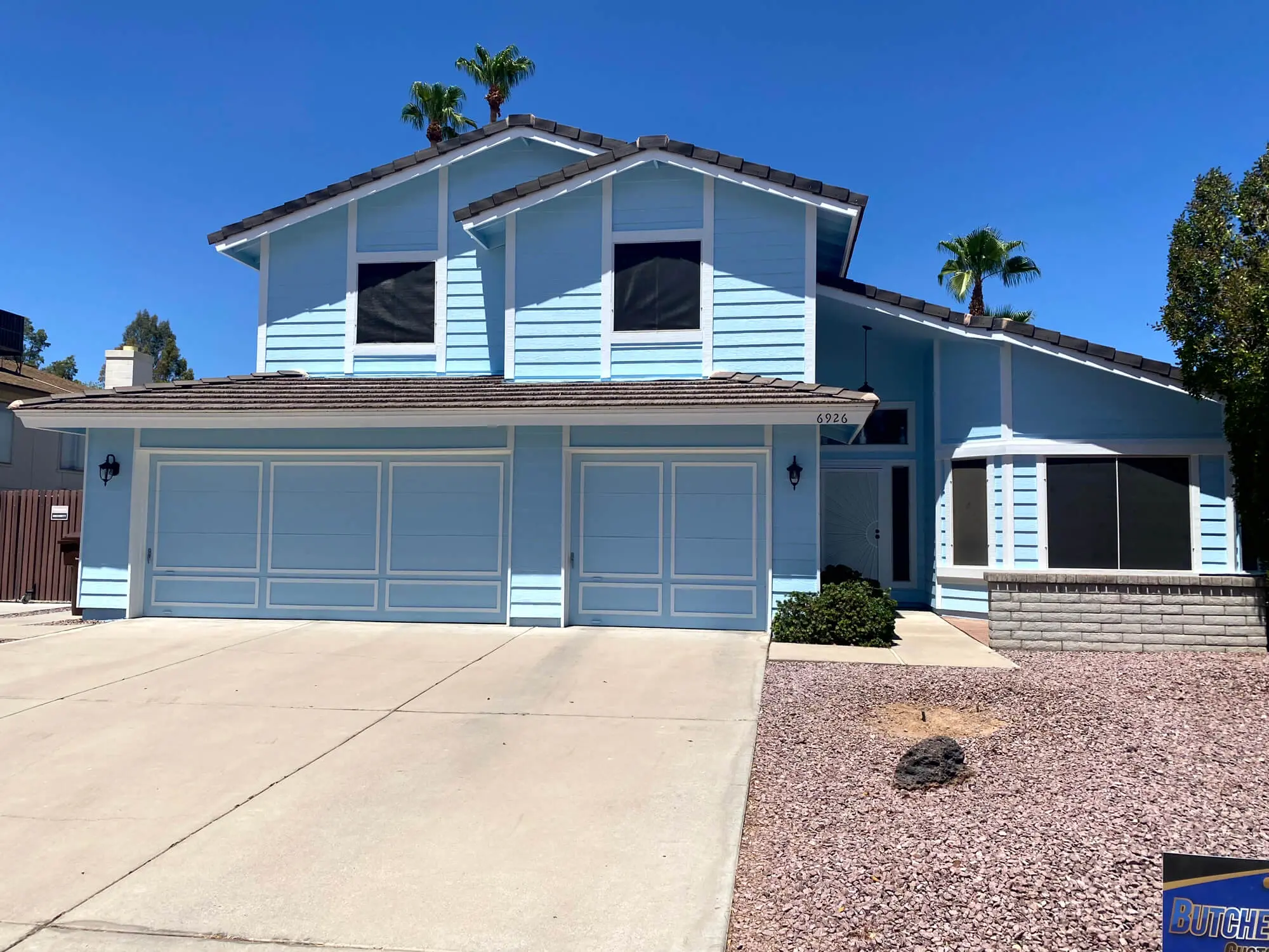 Modern residential exterior featuring a crisp white stucco finish and decorative stone accents, professionally completed by Butchers Custom Painting.