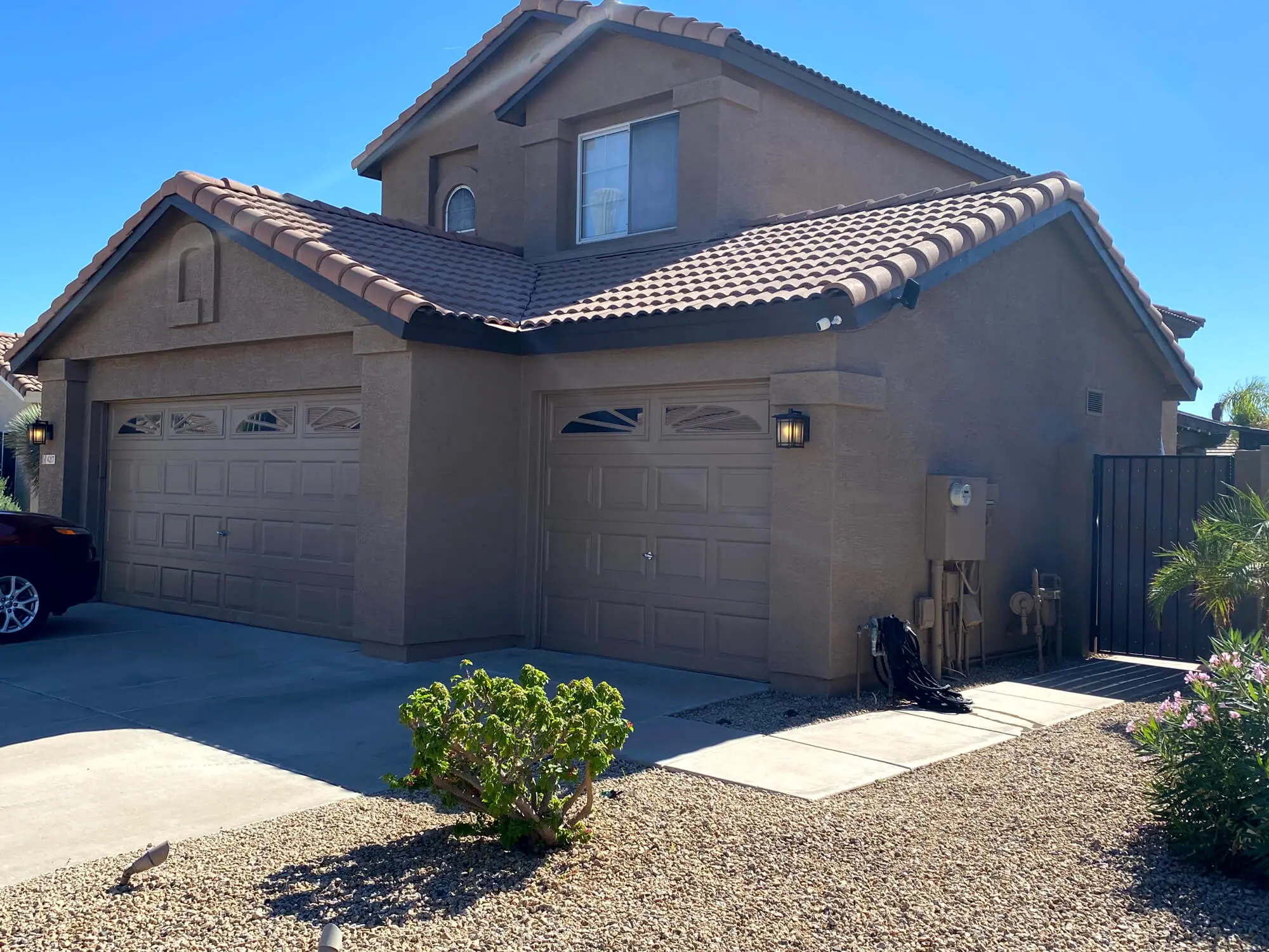 Modern two-story stucco home with tan garage doors and a tiled roof, showcasing a professional exterior finish by Butchers Custom Painting.