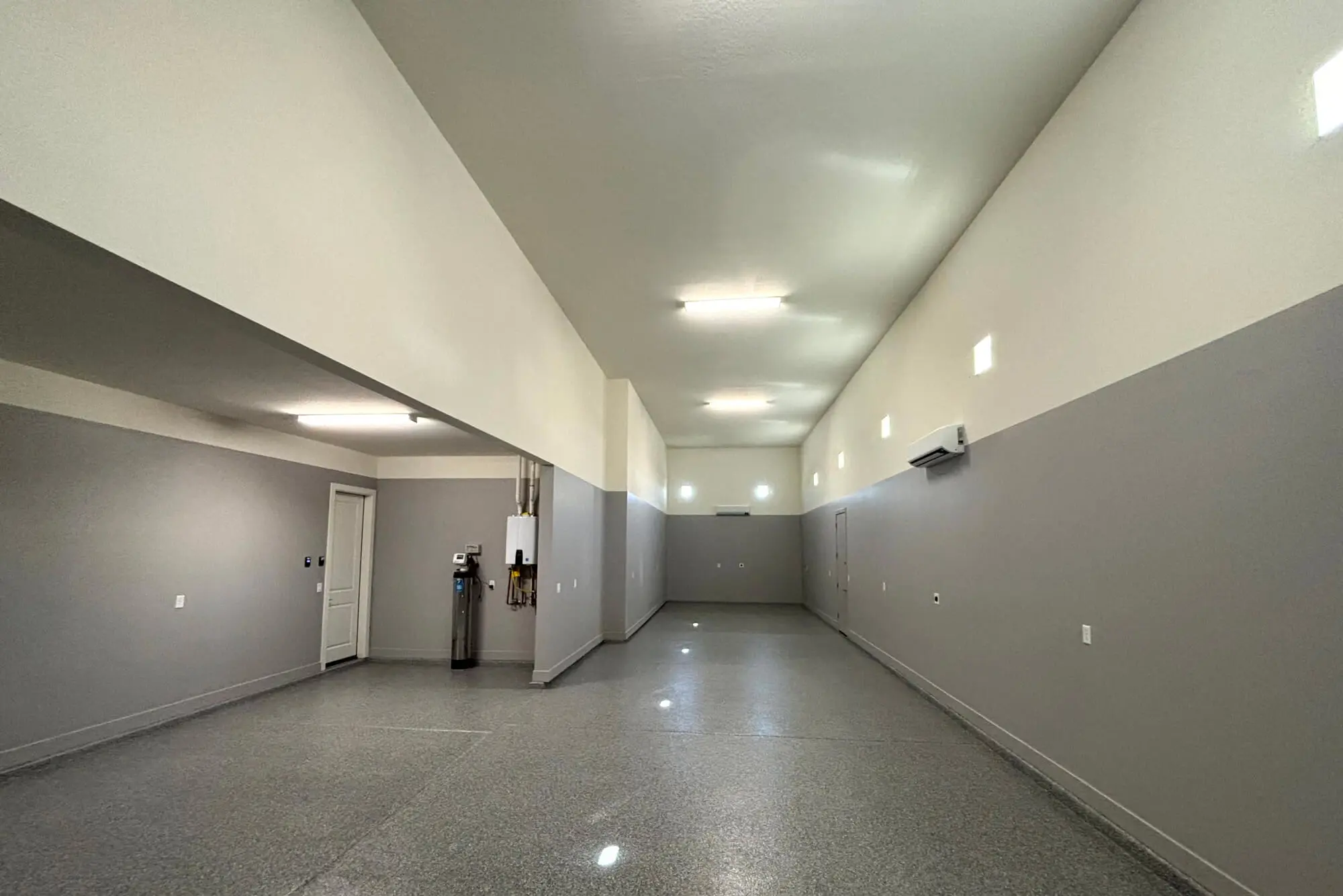 Spacious commercial or residential garage with a high-gloss floor and clean two-tone gray and white walls, expertly finished by Butchers Custom Painting.