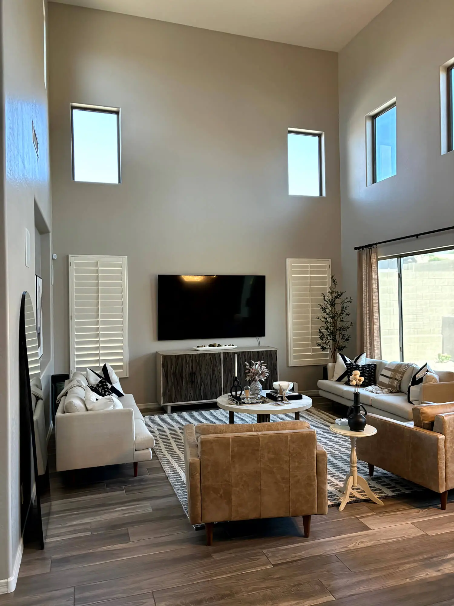 Modern high-ceiling living room with neutral walls and professional interior paint finishes by Butchers Custom Painting.