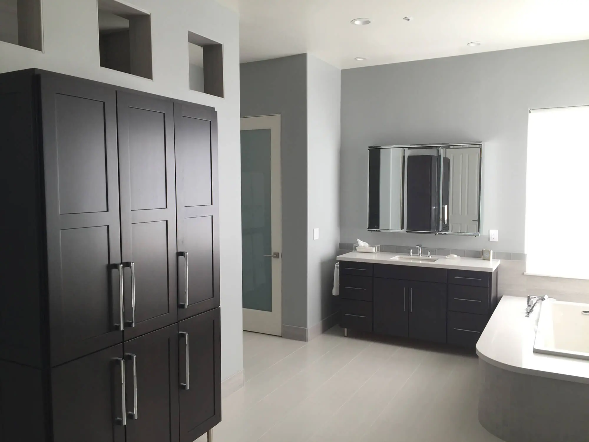 Modern master bathroom with light gray walls and dark wood cabinetry, showcasing expert interior finishes by Butchers Custom Painting.