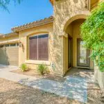 A stucco home with a tile roof and desert landscaping in a Peoria, Arizona HOA community.