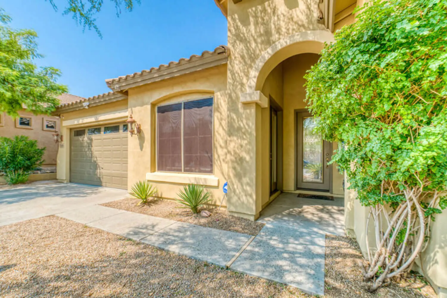 A stucco home with a tile roof and desert landscaping in a Peoria, Arizona HOA community.