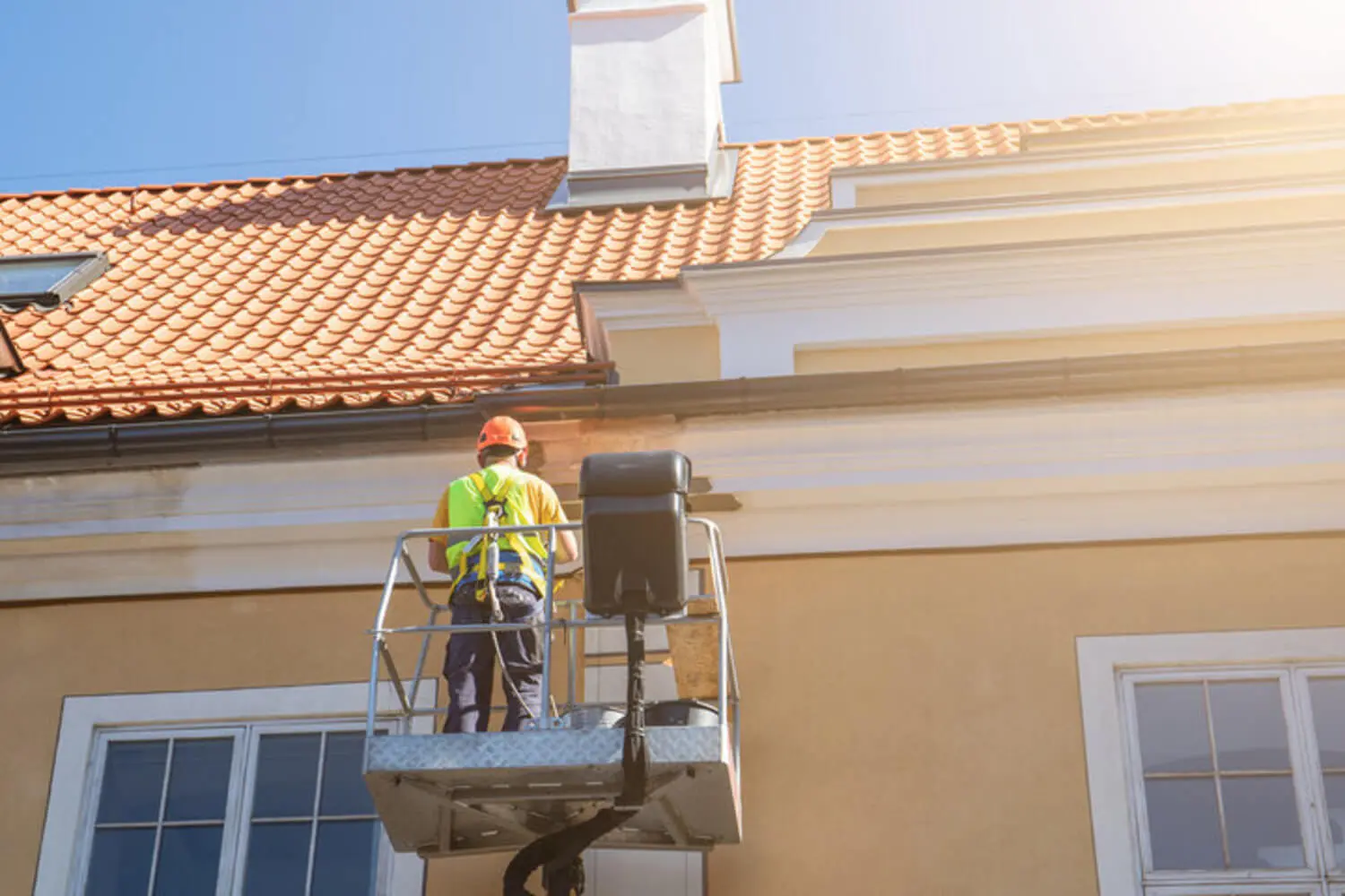 A professional painter on a lift working on a stucco home exterior in Peoria, Arizona backed by a workmanship warranty.
