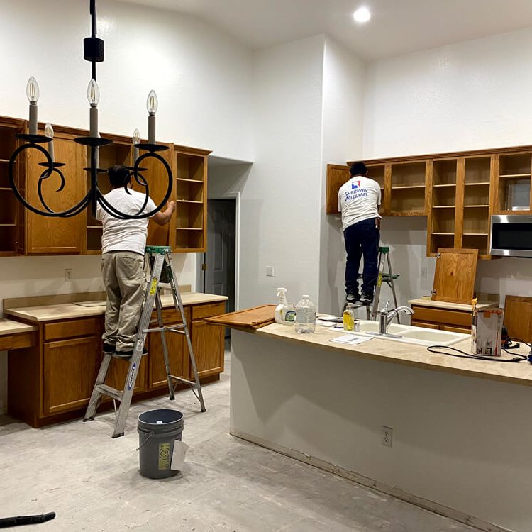 Butcher’s Custom Painting team prepping and refinishing kitchen cabinets during an in-home project